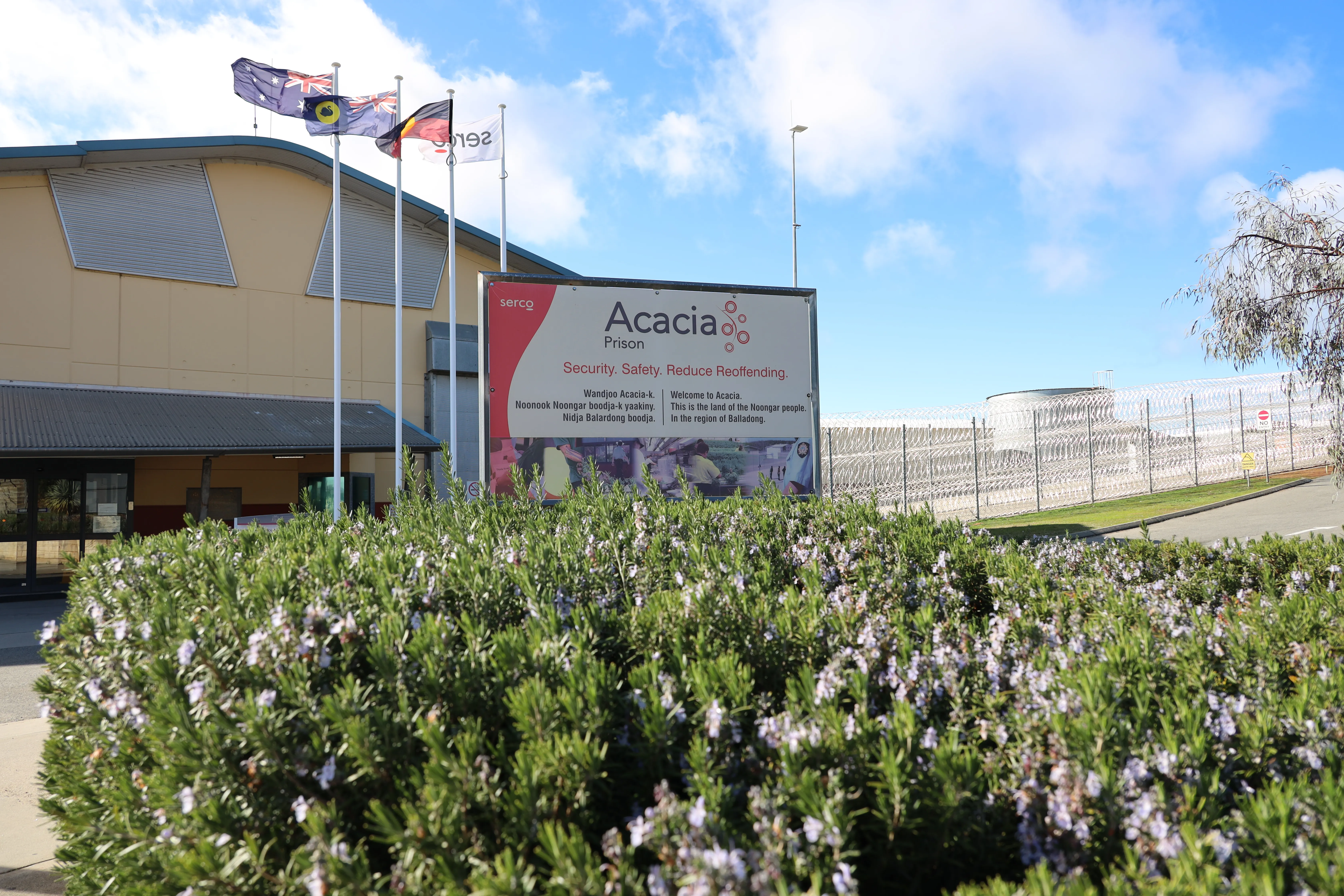 Front entrance of Acacia prison building with a large sign displaying prison name in the foreground. 