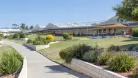 Front entrance of the prison showing a walkway with a building and grass and bushes